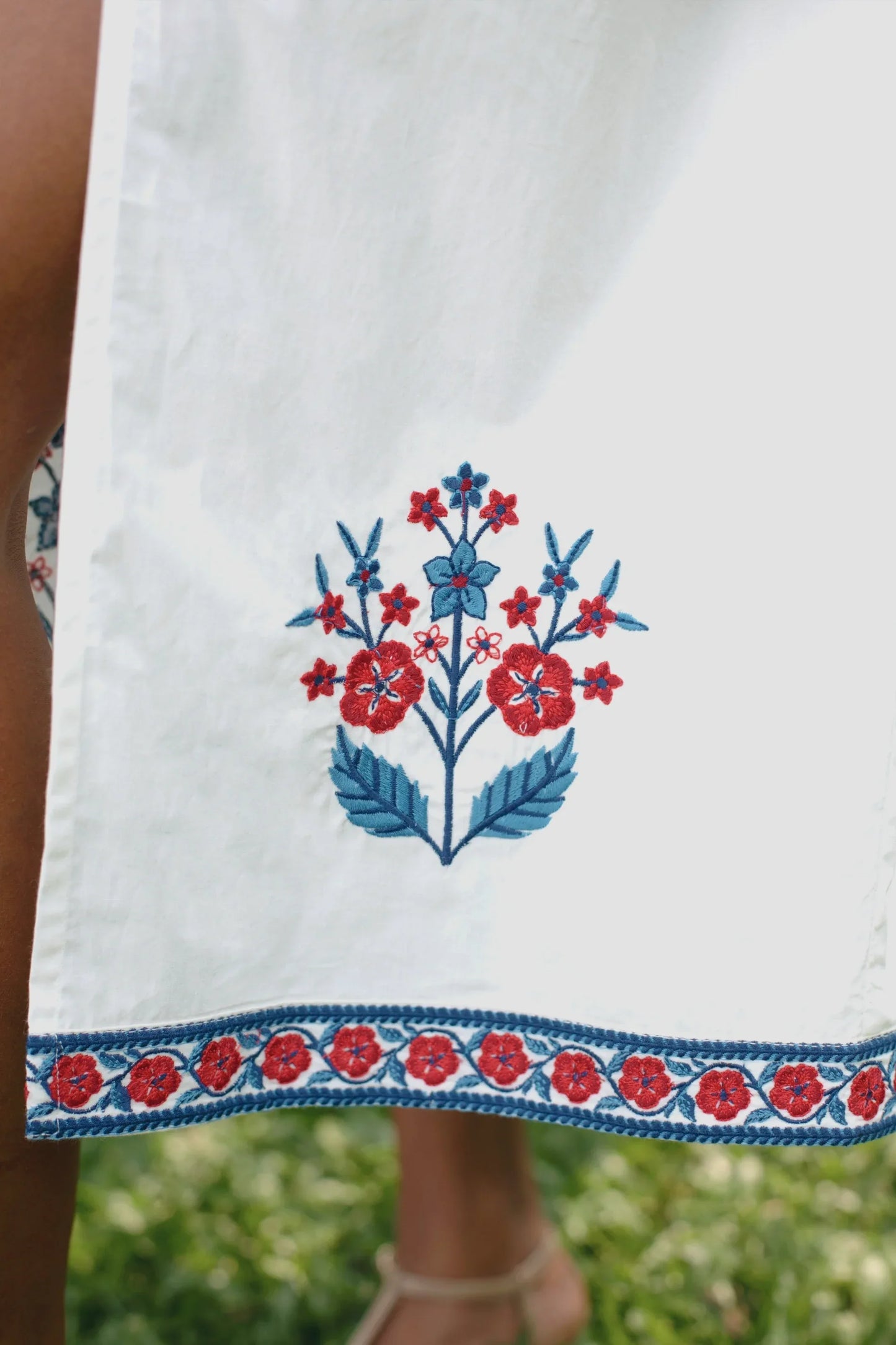 Close-up of delicate red and blue floral embroidery on white cotton midi dress, it also shows 100% cotton poplin fabric — Amaya World