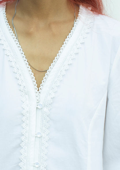 Detail picture of the neckline of white puff sleeve blouse with lace trim detail