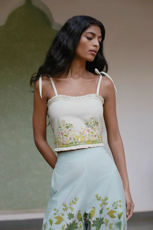Front view of Off white botanical Chintz print cotton crop top with sweetheart neckline and tie-up straps  style with blue floral high wasted trousers— Amaya World