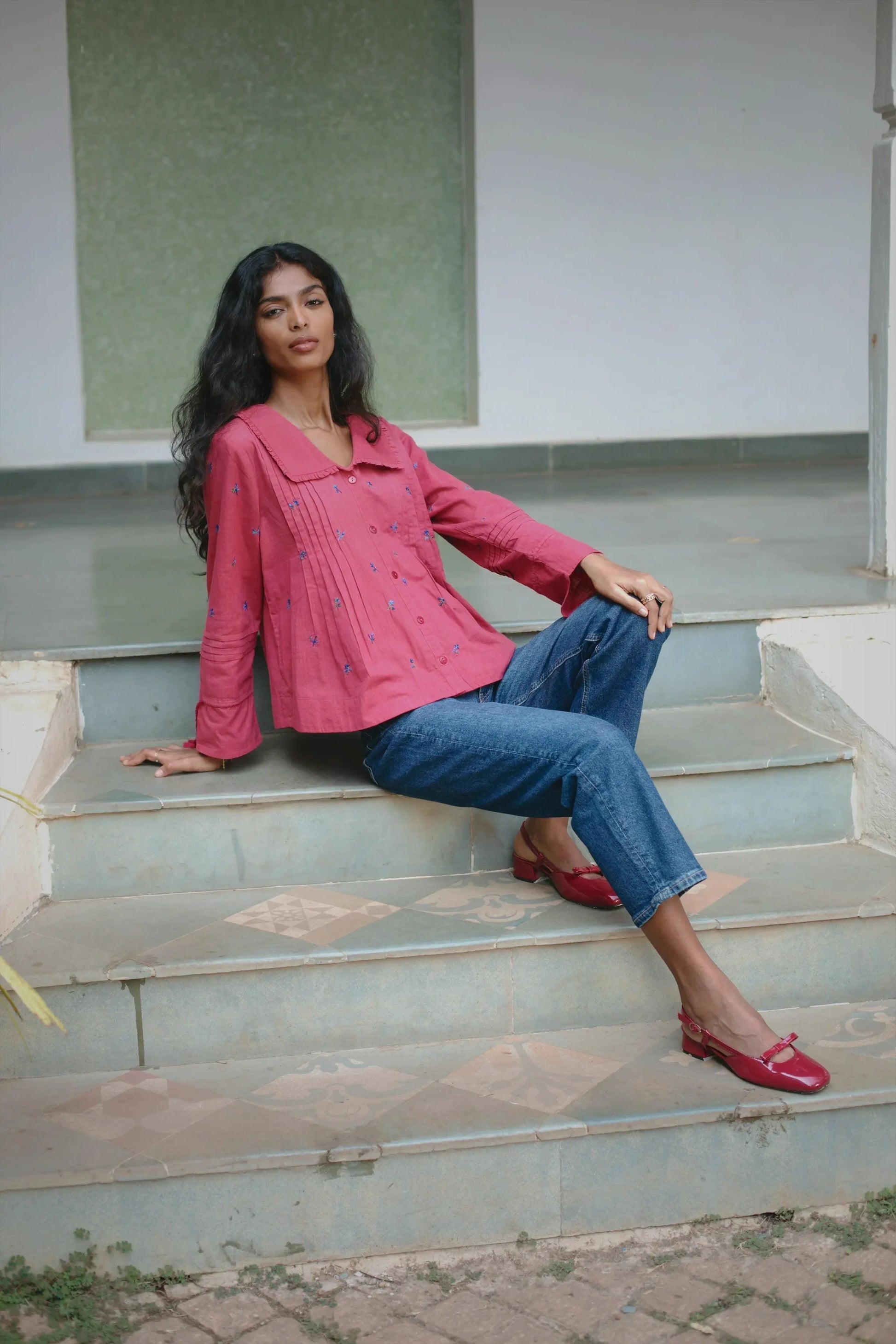 Red embroidered cotton linen boho blouse with oversized collar and tassel on sleeves styled with blue jeans— Amaya World