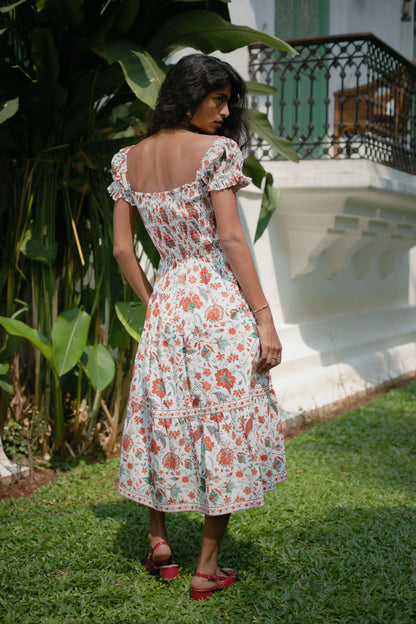 Back view of red Chintz floral midi dress showing smocked bodice, short puff sleeves and elasticated fit — Amaya World