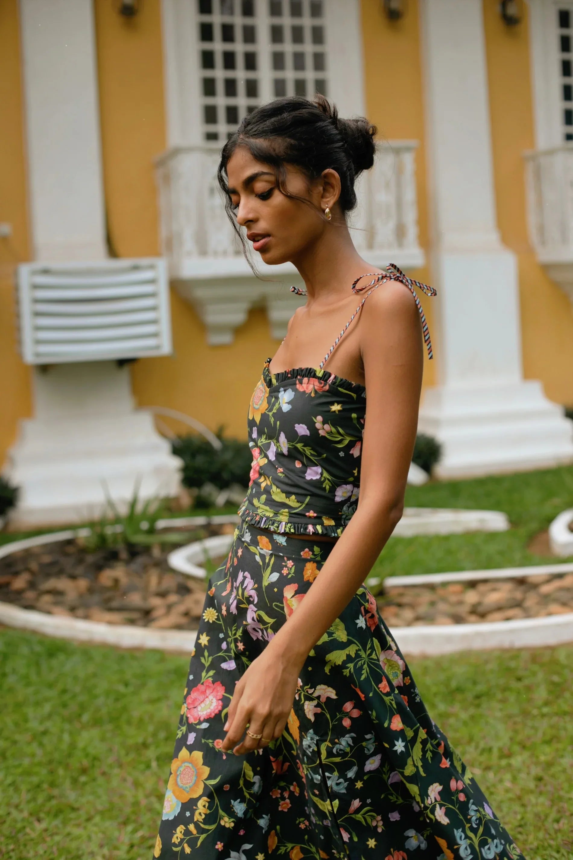 Side view of black high-waist floral midi skirt showing elasticated waist and side zip styled with black floral crop top with tie-up straps and sweetheart neckline— Amaya World
