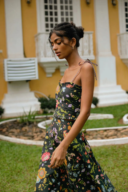 Side view of black high-waist floral midi skirt showing elasticated waist and side zip styled with black floral crop top with tie-up straps and sweetheart neckline— Amaya World