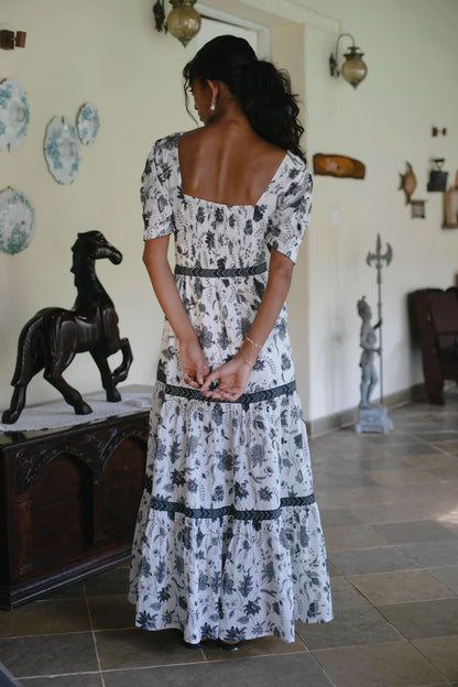Back view of white maxi dress with square neckline and puff sleeves. This floral boho maxi dress showcases the elastic in the back and the full length of the dress  — Amaya World