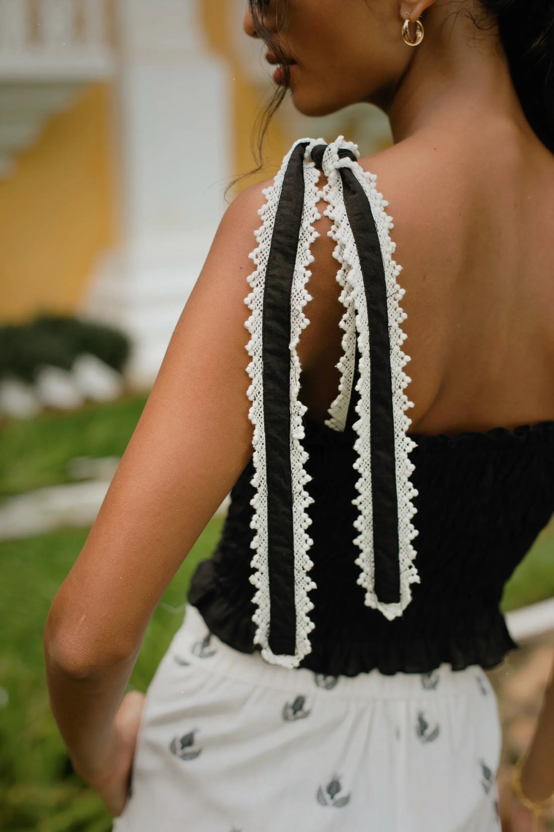 Close-up black crop top with smocked boddice and tie-up straps finished with a delicate white lace - Amaya World
