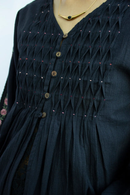Detail picture of black embroidered long sleeve cotton top showing v neckline and pleat detail