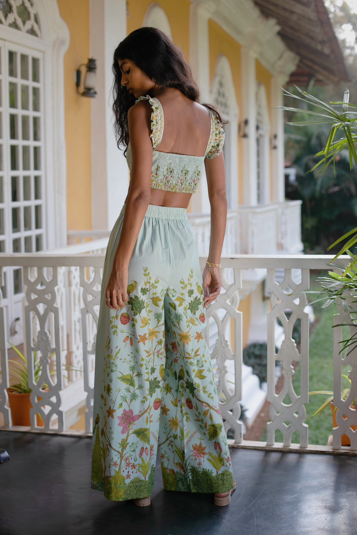 Back view of Blue Floral Chintz inspired botanical print high-waisted wide-leg cotton trousers styled with blue floral bralet crop top— Amaya World handmade slow fashion