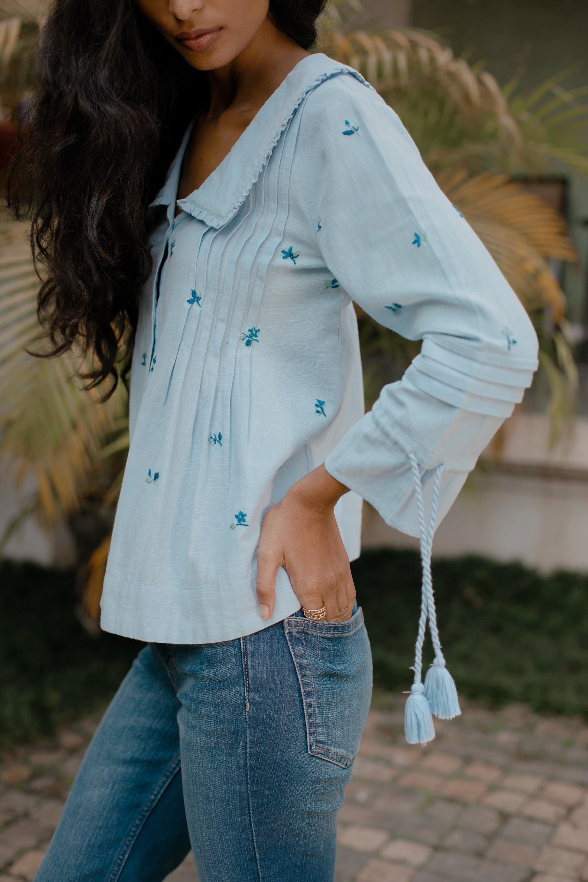 Side view of Light blue hand-embroidered cotton linen boho blouse with oversized frill collar and tassel sleeves — | Amaya World