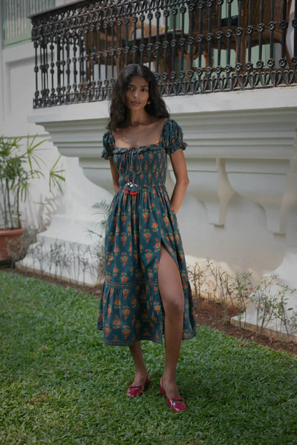 Front view of navy hand-painted Chintz floral fit-and-flare cotton midi dress with smocked bodice, short puff sleeves and tassles — Amaya World