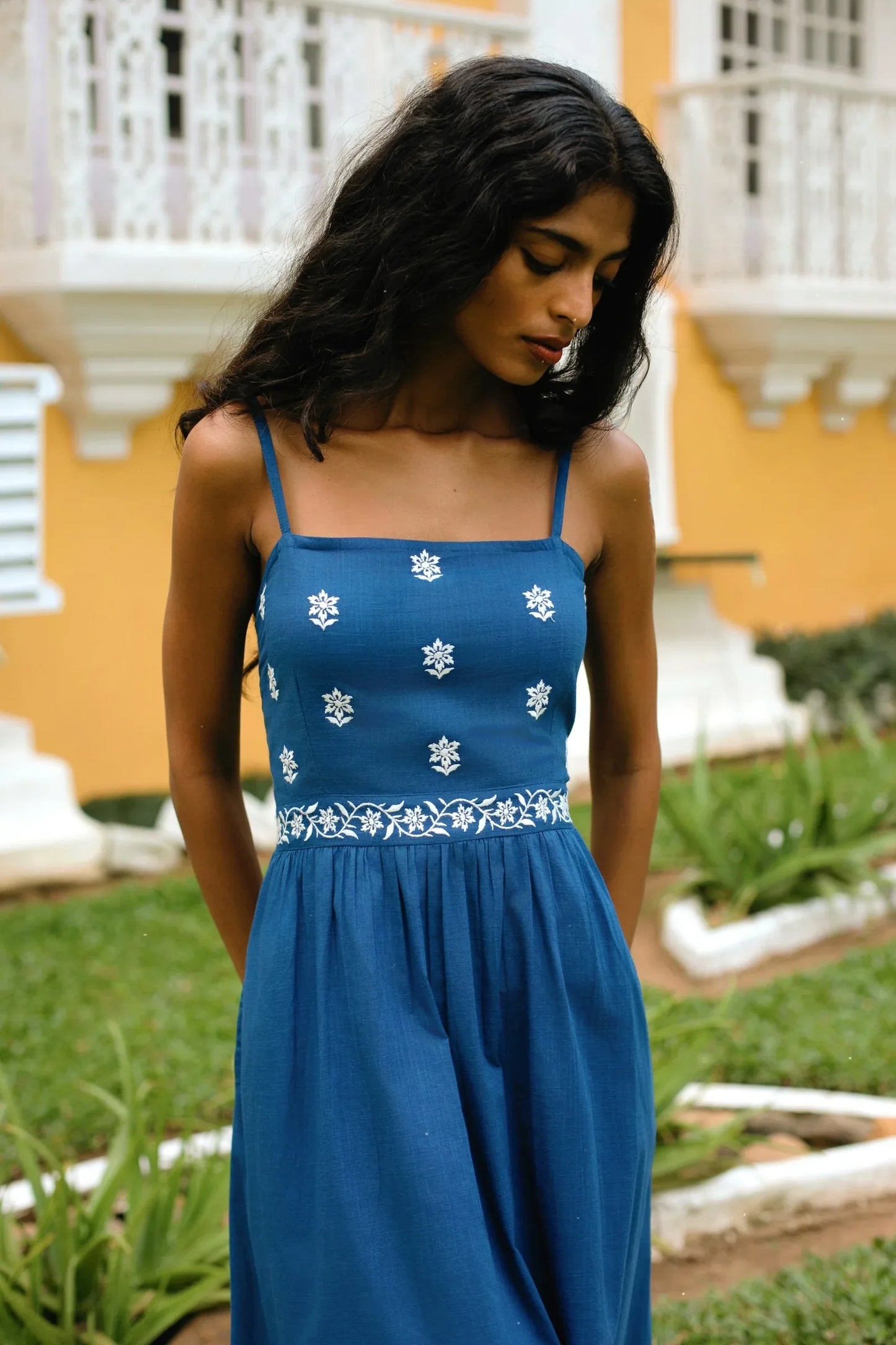 Close-up of model wearing blue boho midi dress with Spaghetti straps, highlighting the 100% cotton linen fabric texture and white embroidered motifs — Amaya World