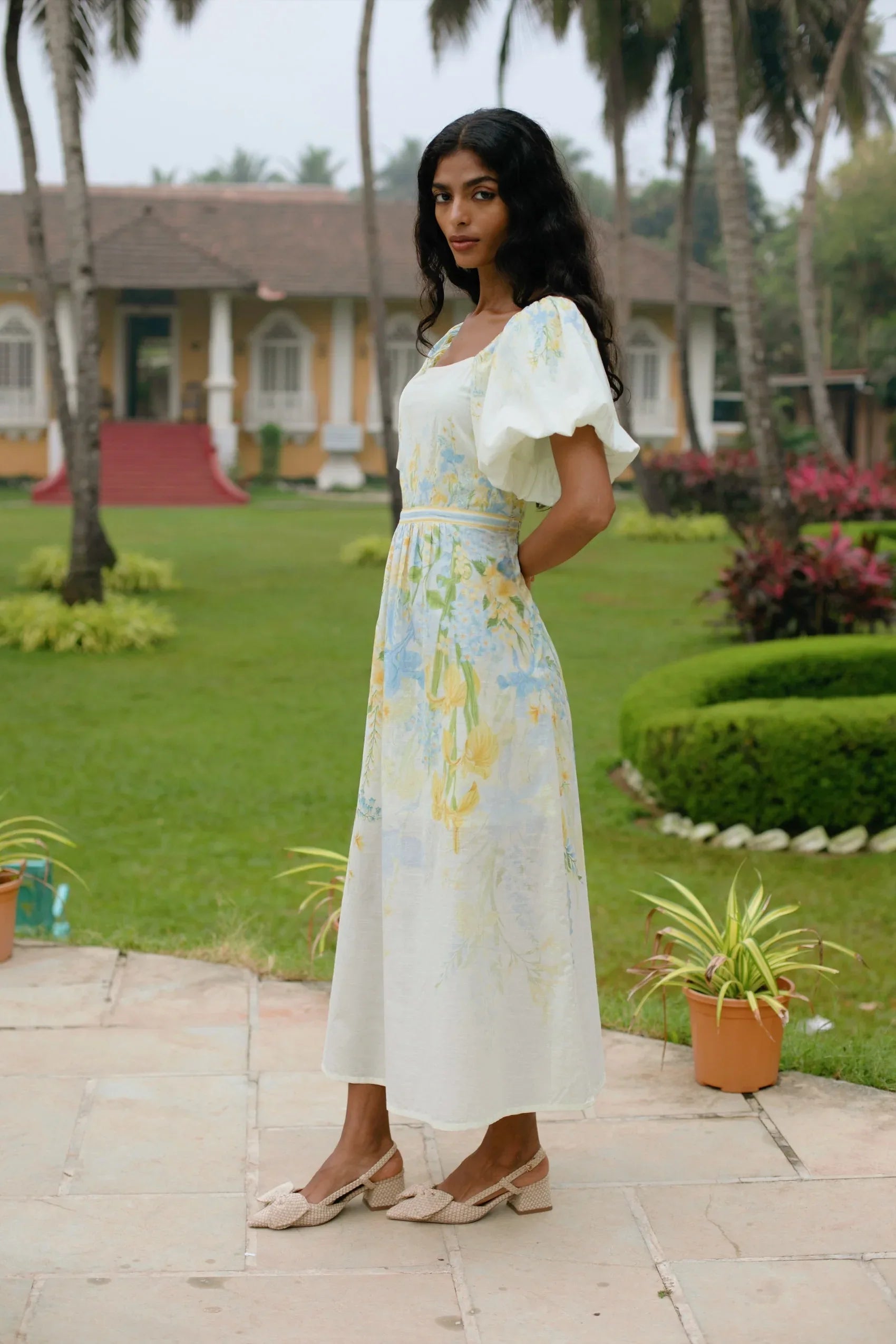 Side view of yellow floral puff sleeve cotton midi dress styled for brunch — Amaya World slow fashion