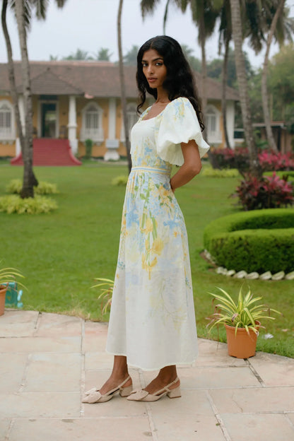 Side view of yellow floral puff sleeve cotton midi dress styled for brunch — Amaya World slow fashion